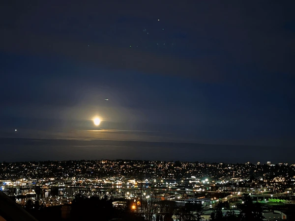 A calm night scene with a moonlit sky, soft city silhouettes, and a warm ambient glow representing a peaceful evening wind-down